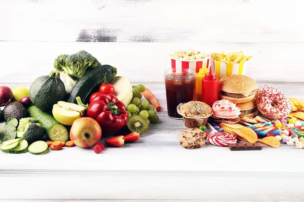 Légumes et fruits frais à côté de fast-food sur une table